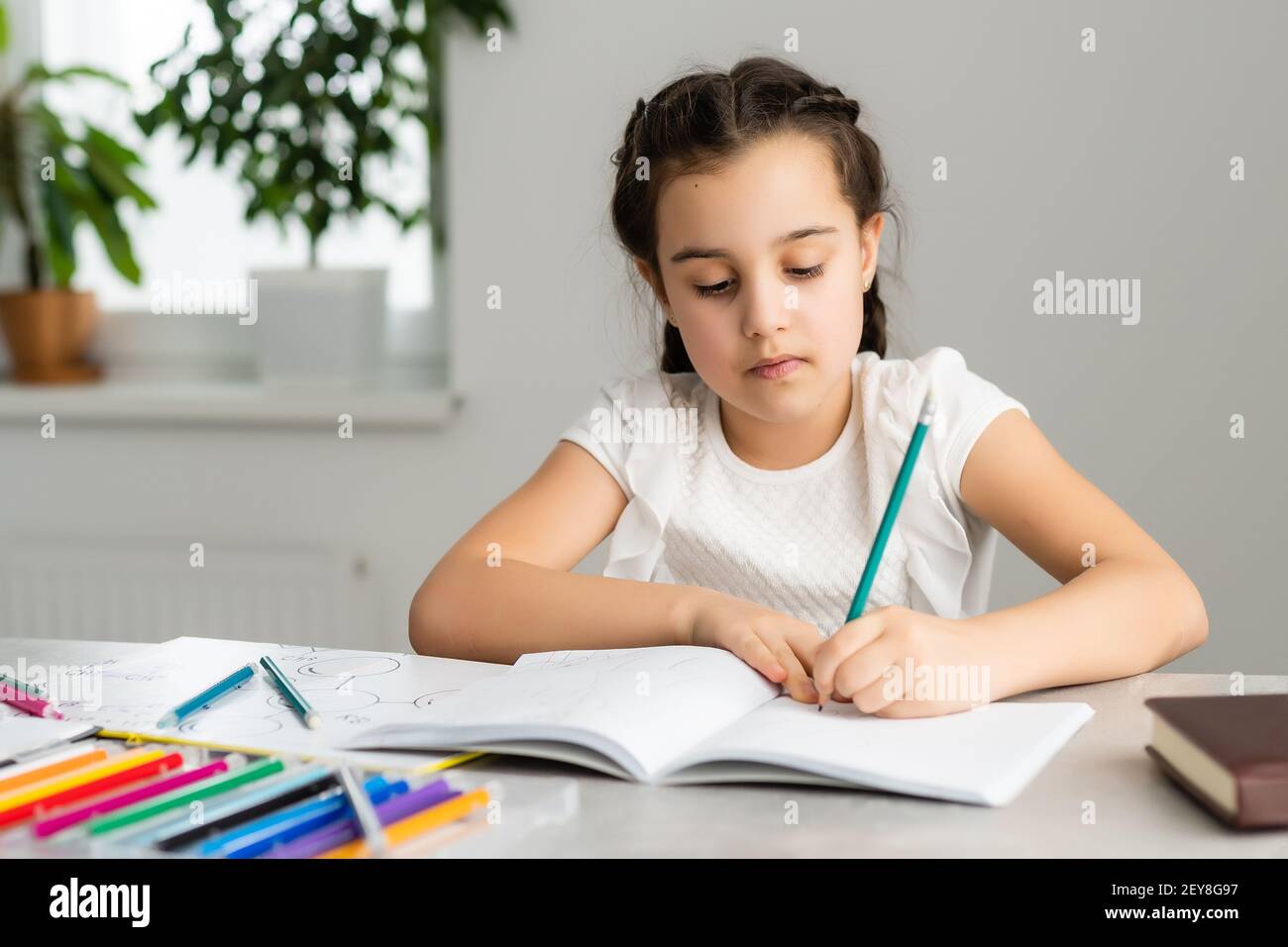 Cute little girl studying at home and smiling Stock Photo - Alamy