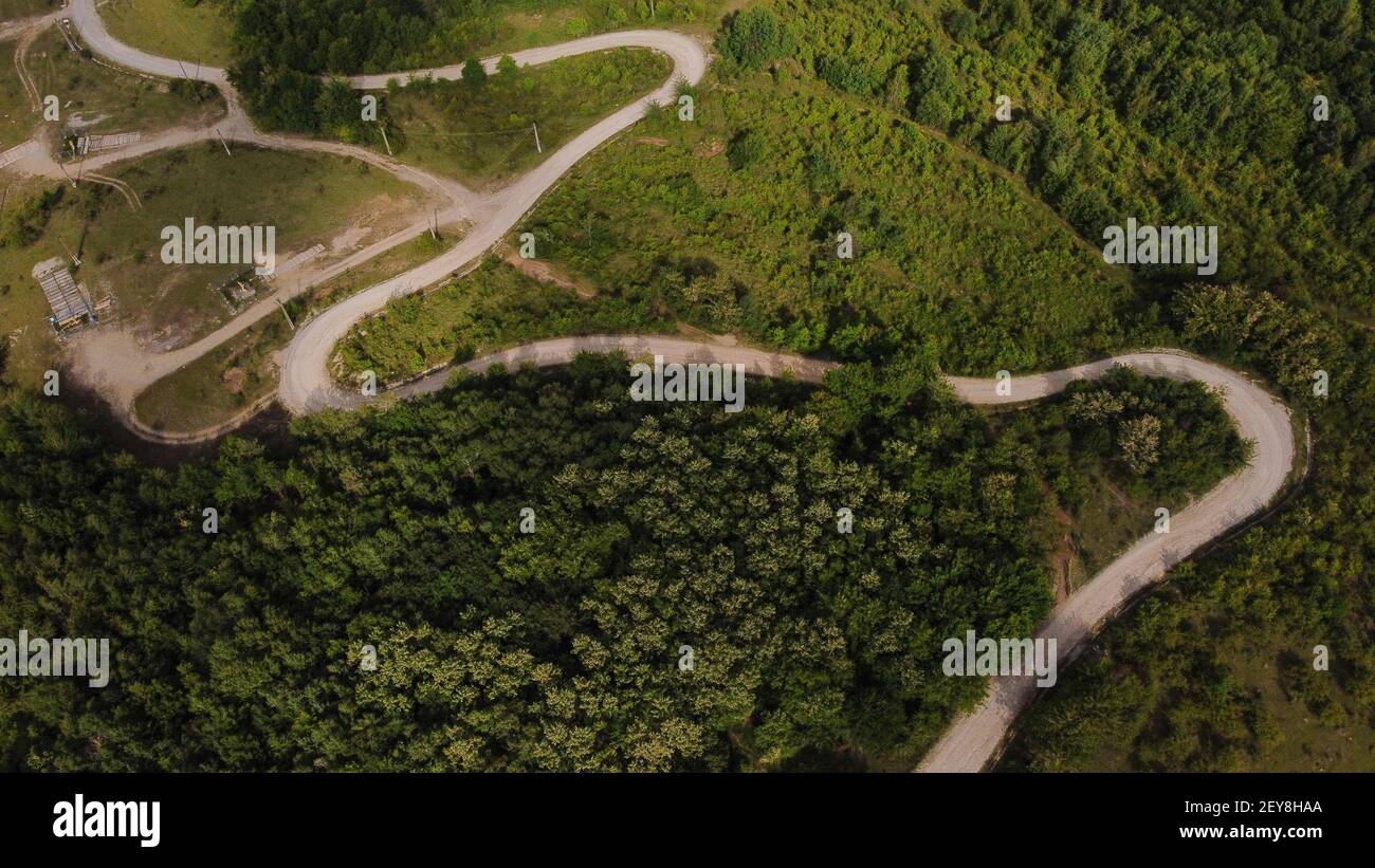 An aerial view of a winding road surrounded by greens and trees Stock ...