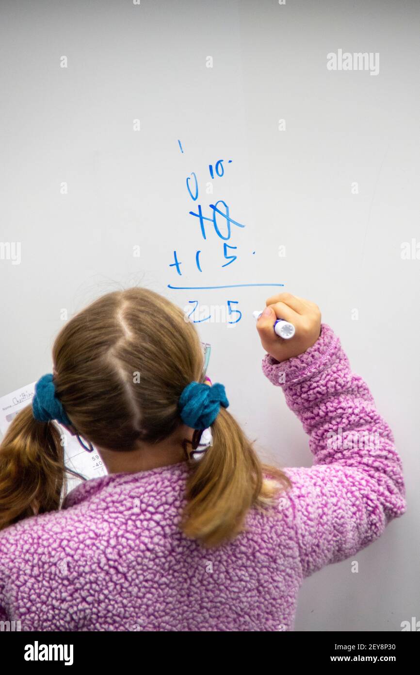 A California elementary school student demonstrates addition on the classroom white board. Stock Photo