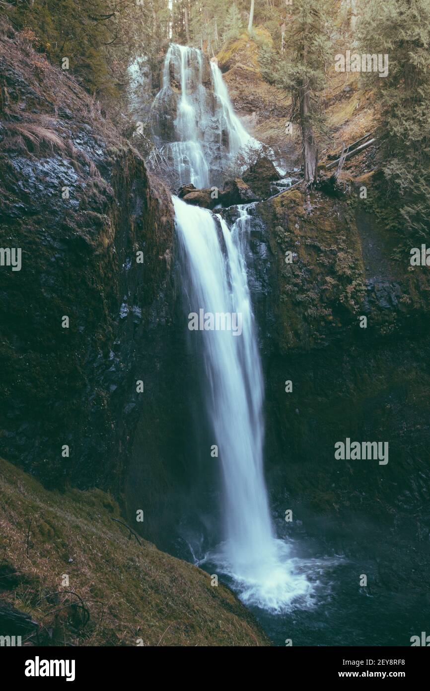 A vertical shot of a waterfall on the mountains captured in the middle ...