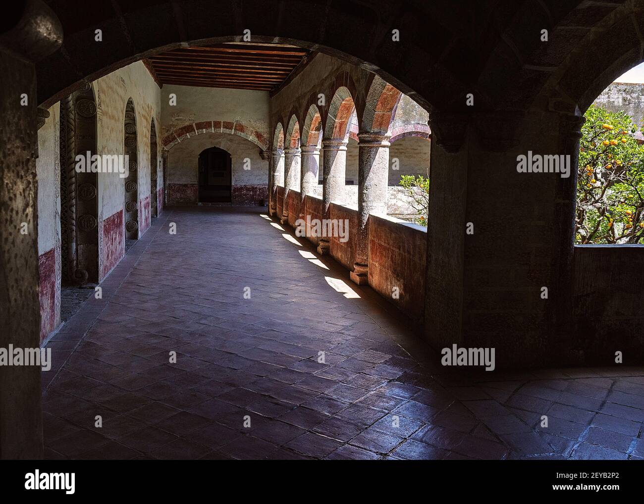 Corridor in a XVI century former Franciscan convent, where lights and shadows create an atmosphere of mysticism to visitors Stock Photo