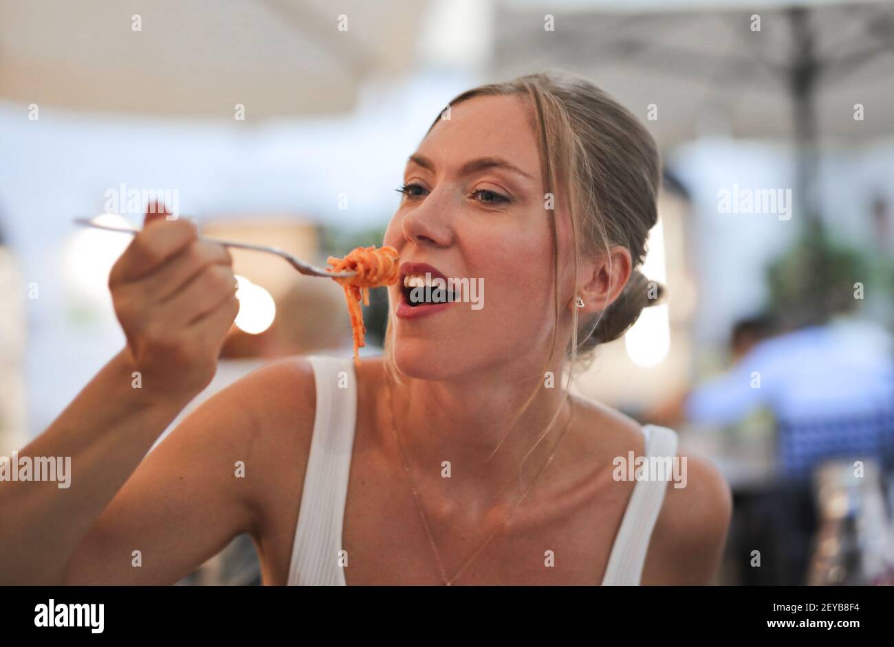 A young European female eating spaghetti in a restaurant Stock Photo