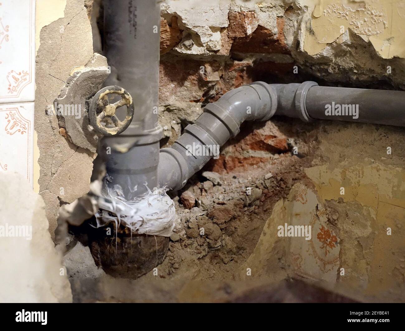 A closeup shot of plumbing pipes installed in the walls under the tiles with valve wheel Stock Photo