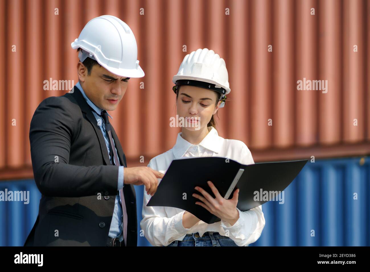 A caucasian man manager explaining logistics transportation system in the container depot terminal to the female secretary. Stock Photo