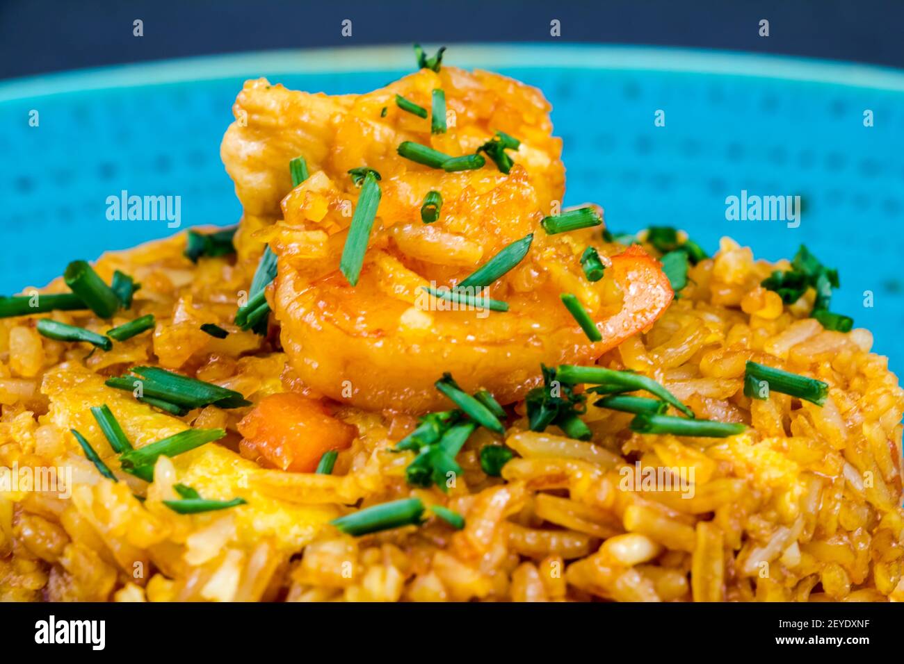 Traditional spanish paella dish with seafood, peas, rice and chicken over grunge blue background. Top view. Selective focus Stock Photo