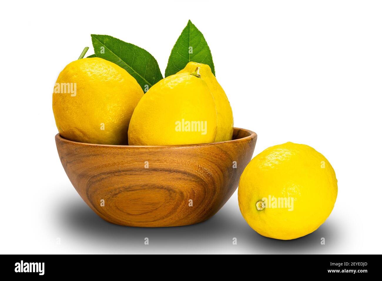 Ripe lemons with leaves in a wooden bowl on white background with clipping path. Stock Photo