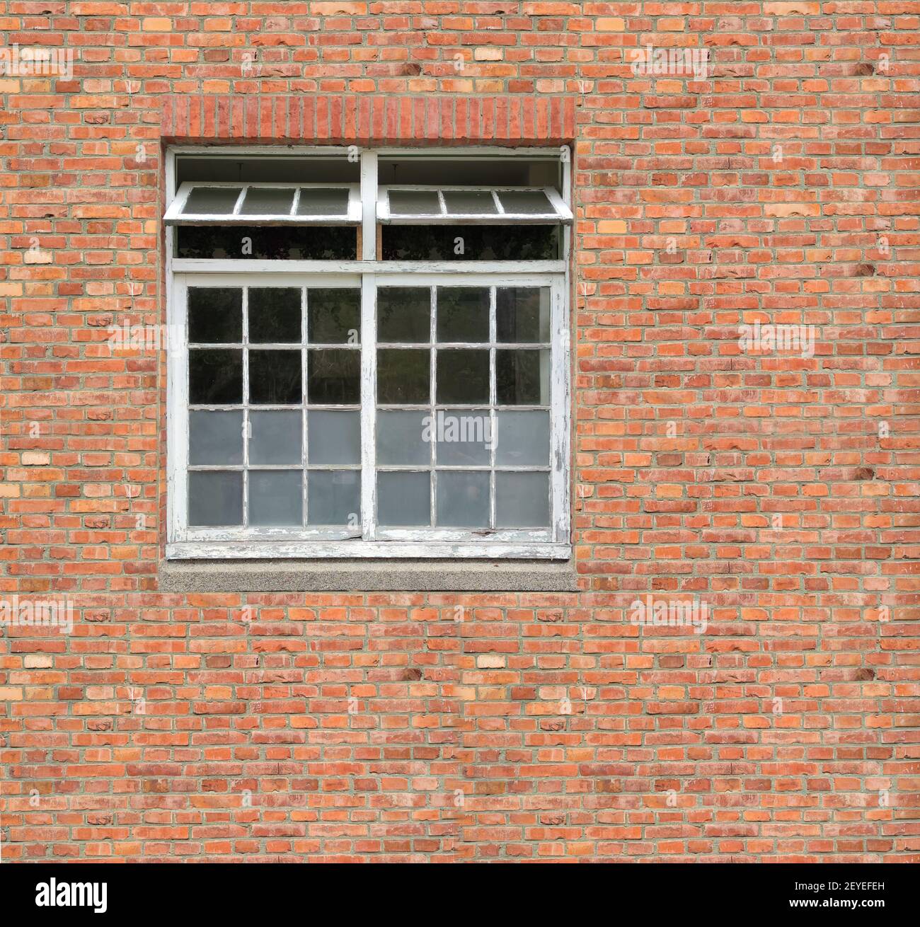 White painted wood arched window in a red brick wall Stock Photo