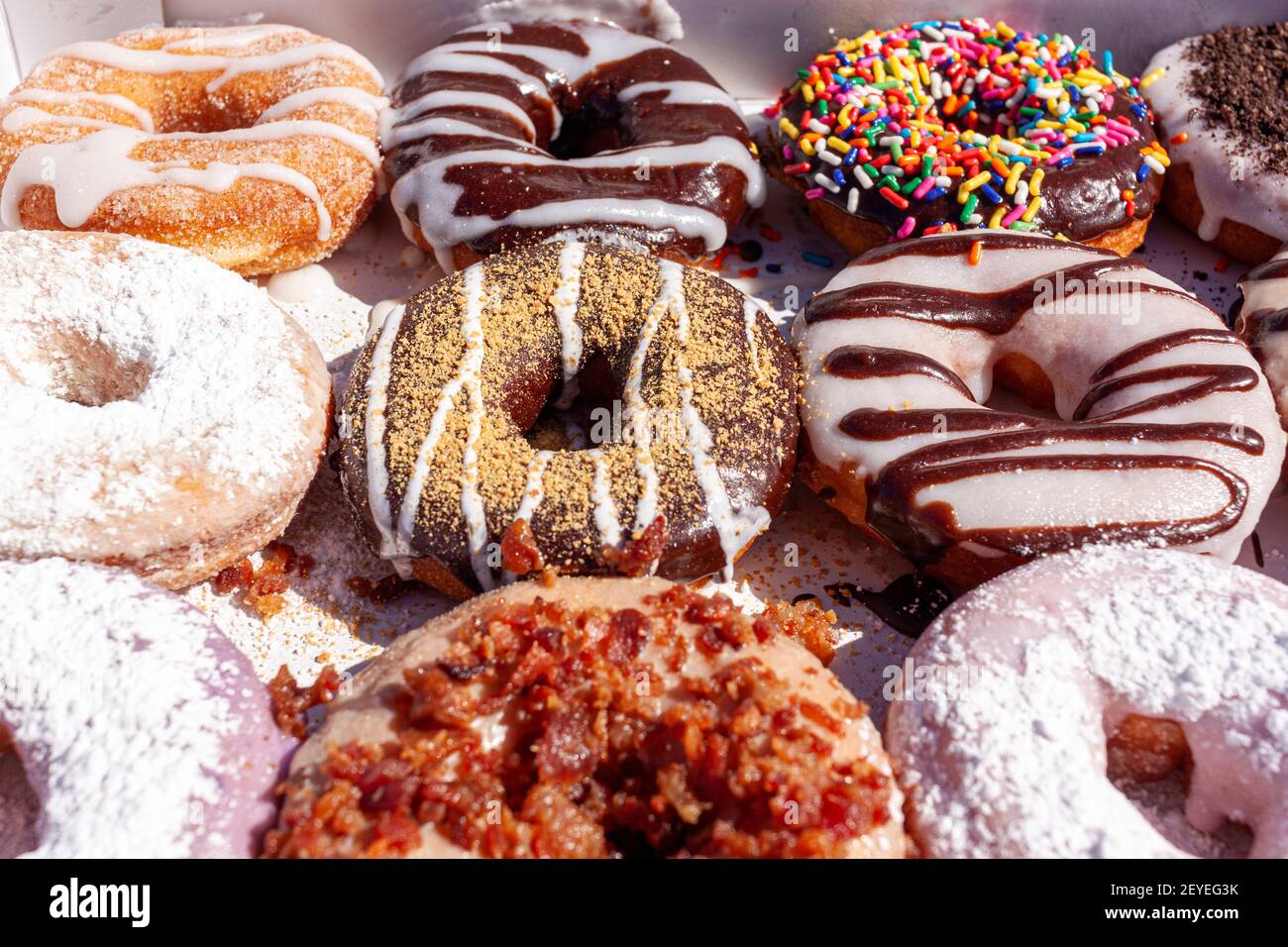 Flat lay image of fresh made store bought donuts in paper box fresh out of the donut shop. An assortment with different flavors and toppings are packe Stock Photo