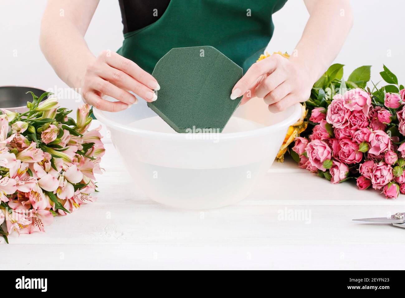 Florist at work: woman shows how to make floral arrangement with roses ...