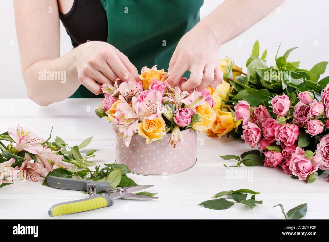 Florist at work: woman shows how to make floral arrangement with roses ...
