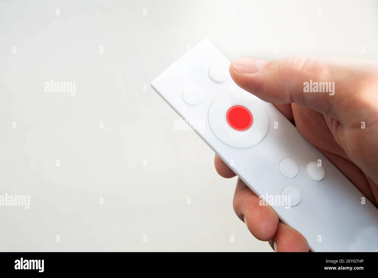 Remote control panel in hand. White remote control for turning on the