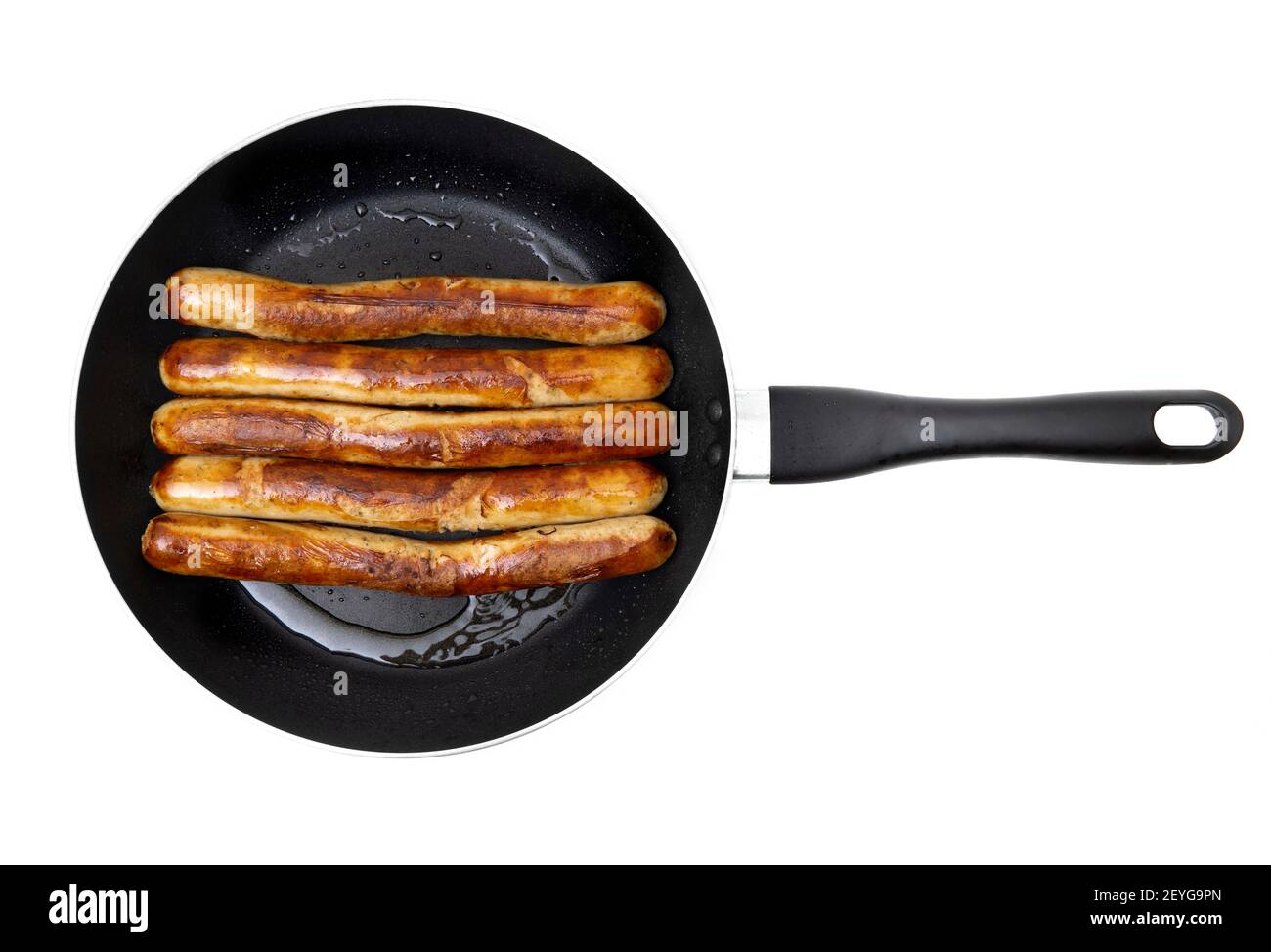 Close-up of five fried traditional german pork sausages on a frying pan isolated on white background. Stock Photo