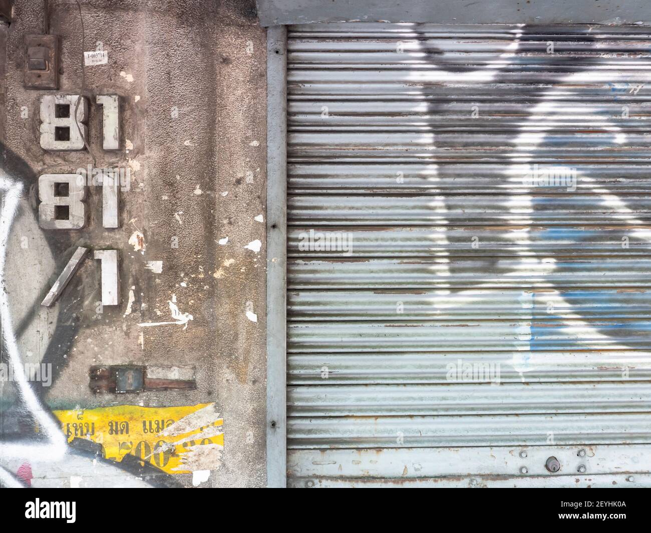 City wall with house number and graffiti and roll up metal door in Bangkok, Thailand. Stock Photo