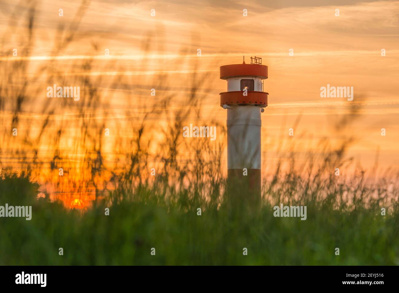 Germany, Lower Saxony, Krautsand: Evening mood. The red-white lighthouse and sunset on the Krautsand Elbinsel. Stock Photo