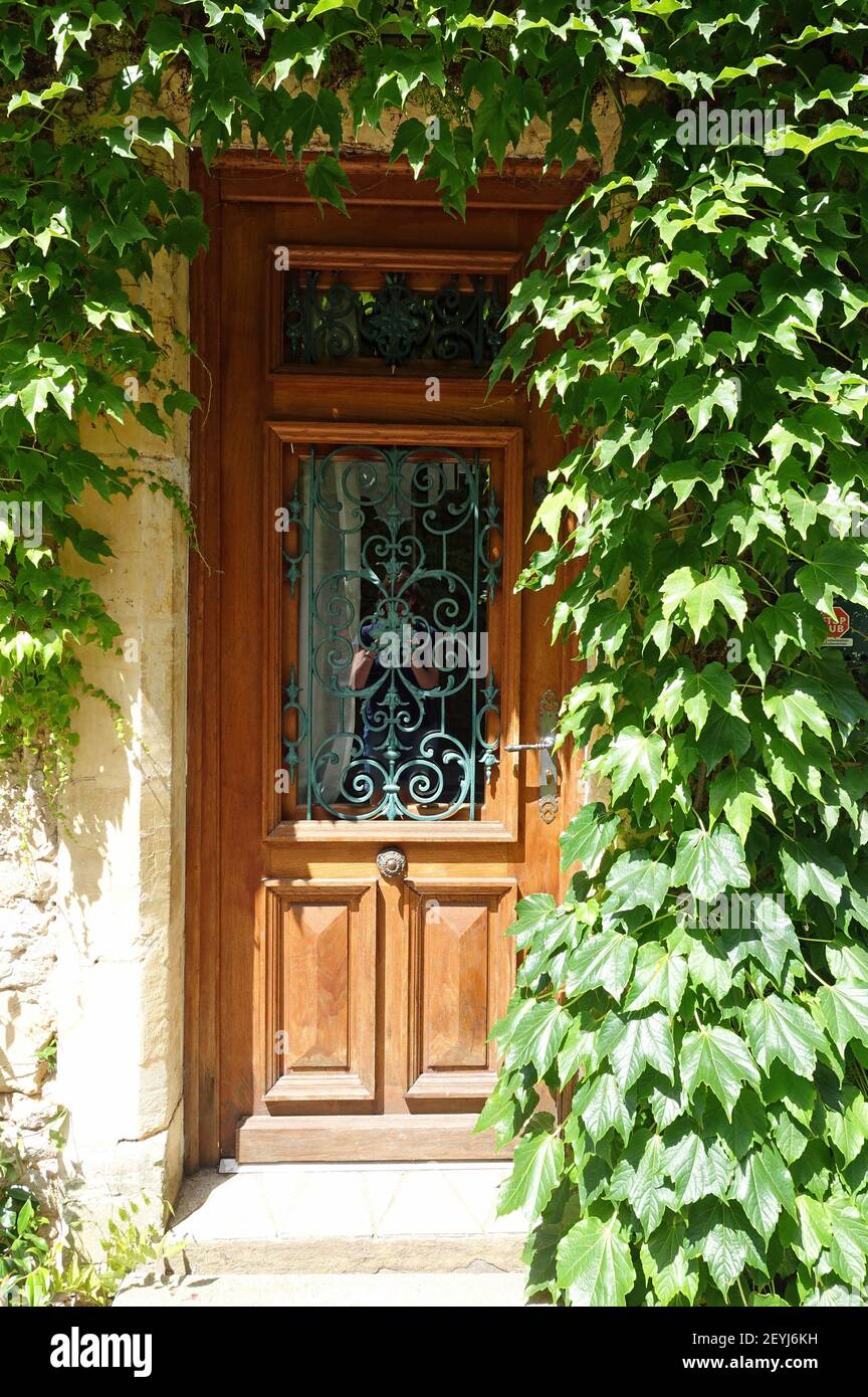 Recessed wooden front door surrounded by ivy Stock Photo