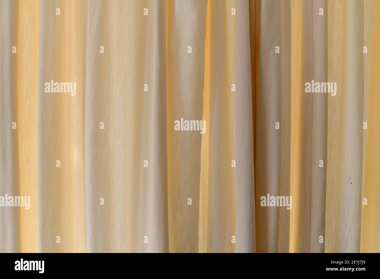 Background of cream curtains backlit by sunlight Stock Photo