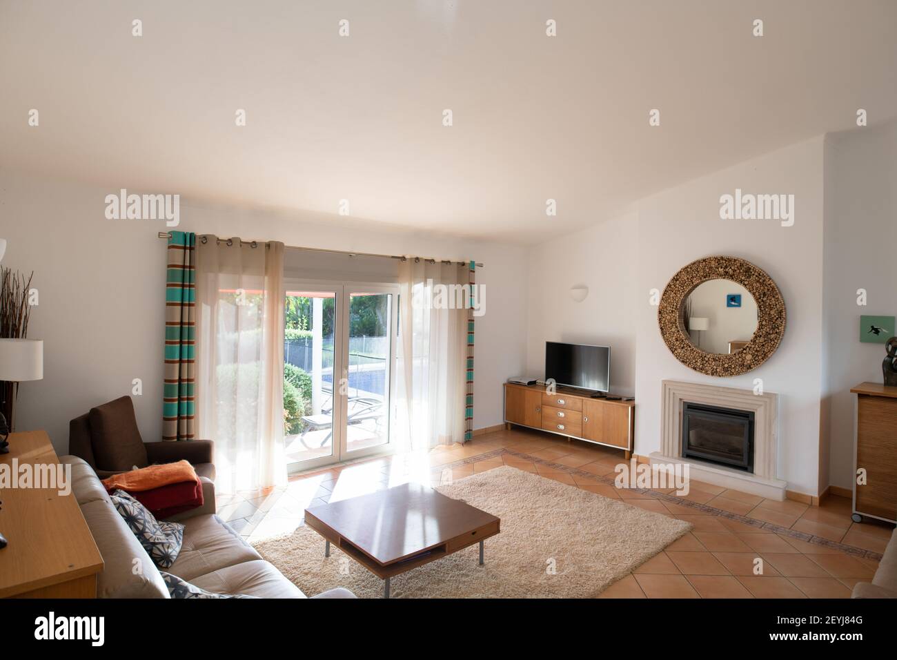 Living room with tiled floors, patio doors and high sloping ceiling Stock Photo