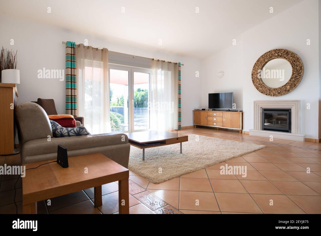 Living room with tiled floors, patio doors and high sloping ceiling Stock Photo
