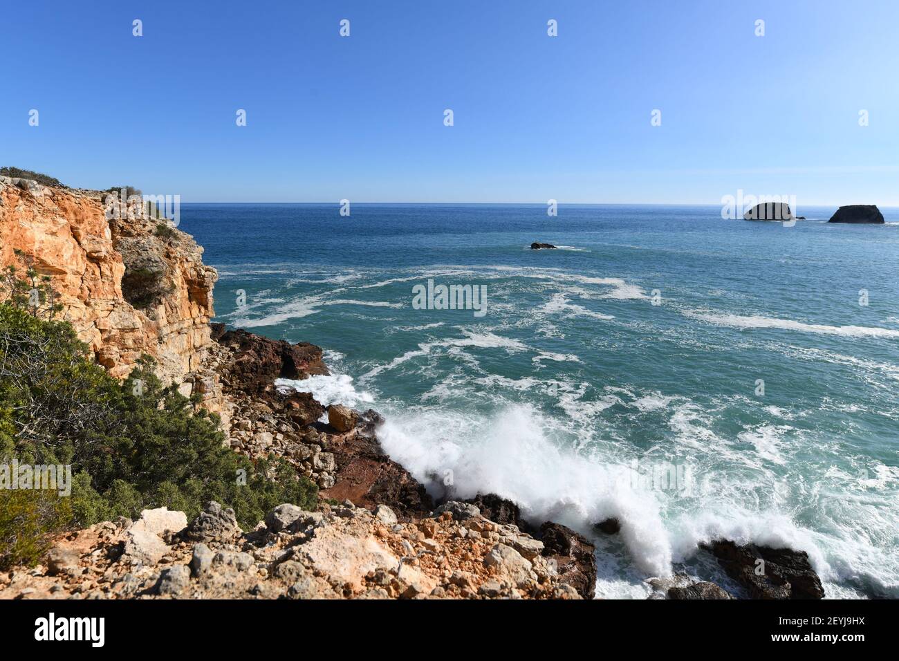 Waves hitting the base of the cliffs on the western Algarve in Portugal Stock Photo