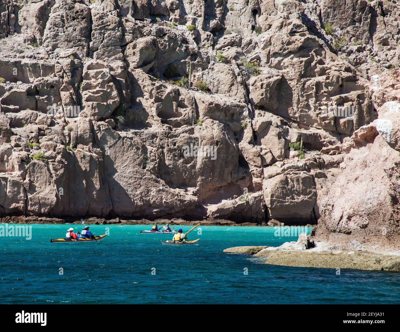 Mighty cliffs dwarf kayakers in Ensenada Grande Cove, Isla Partida, Sea