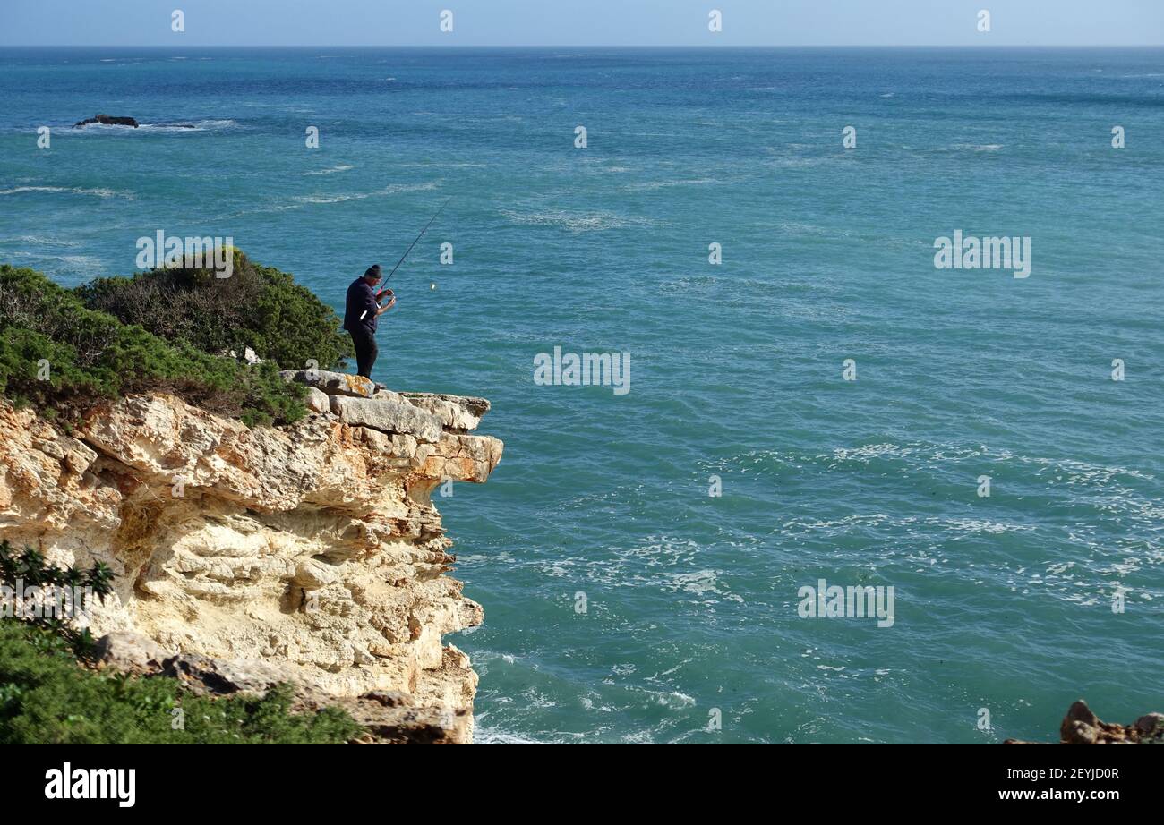 Sagres, Portugal: January 2021; Fisherman fishing from a cliff on the western Algarve coast in Portugal Stock Photo