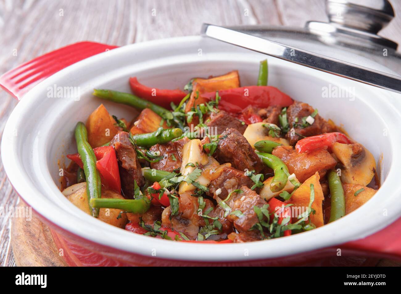 Stewed potatoes with meat and vegetables on a light background Stock Photo