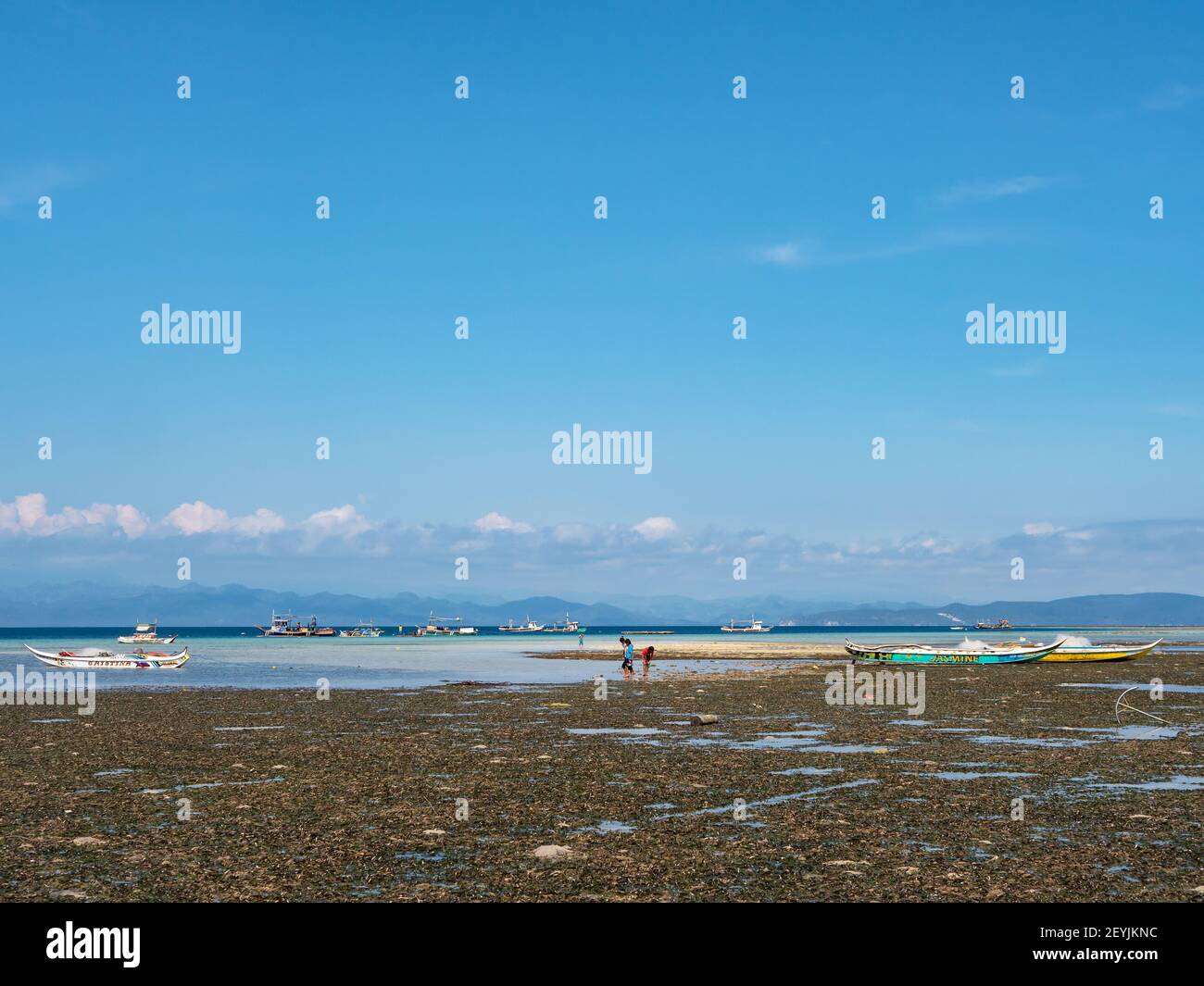 The beach at low tide in Tinoto, a fishing village in Maasim, Sarangani Province of the Philippines. Sarangani Bay with fishing boats and the eastern Stock Photo