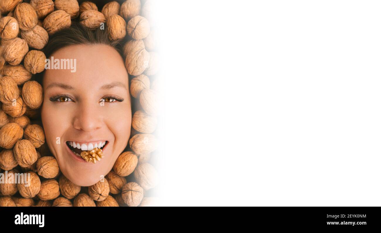 Happy smiling woman face on a walnuts background. Eating nuts. Copy space Stock Photo