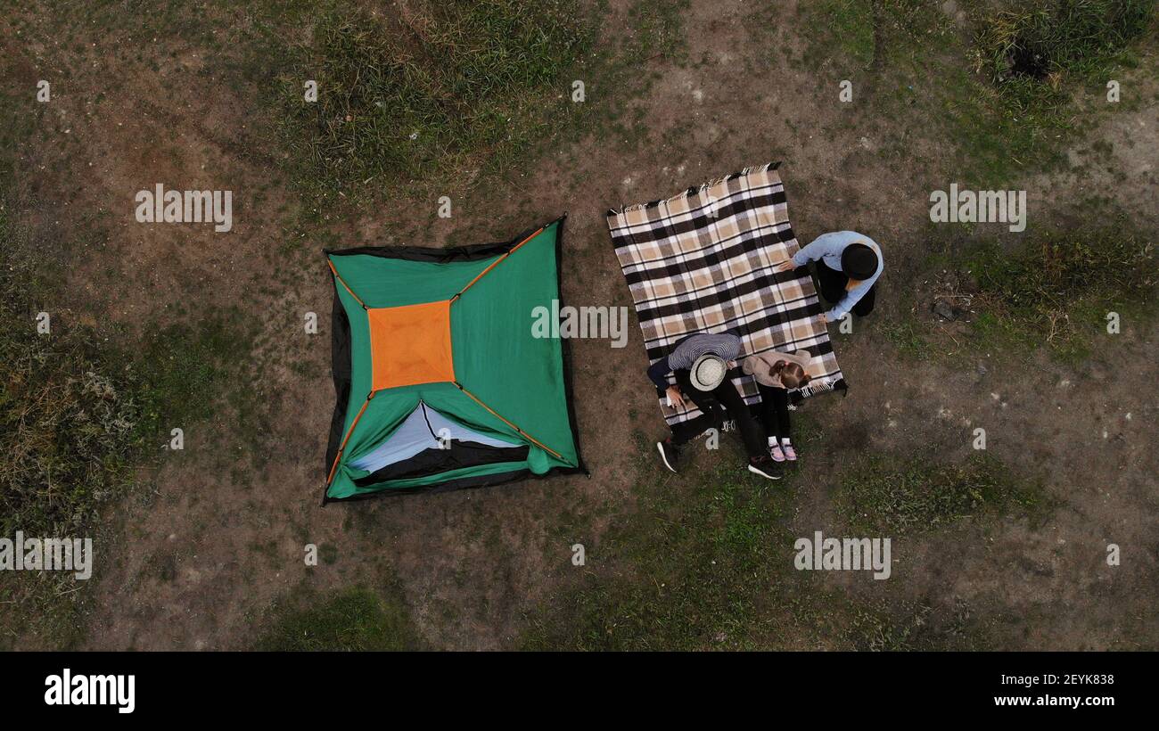 Aerial top view of family in campsite from above, parents and kid relax and lie on plaid, family camp vacation concept Stock Photo