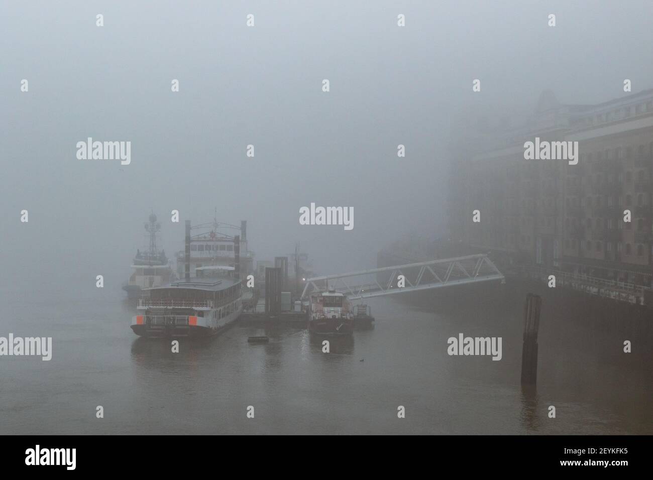 An impressionistic view of boats shrouded in mist, docked by Butlers Wharf in the Pool of London on the River Thames. With copy space - Stock Image