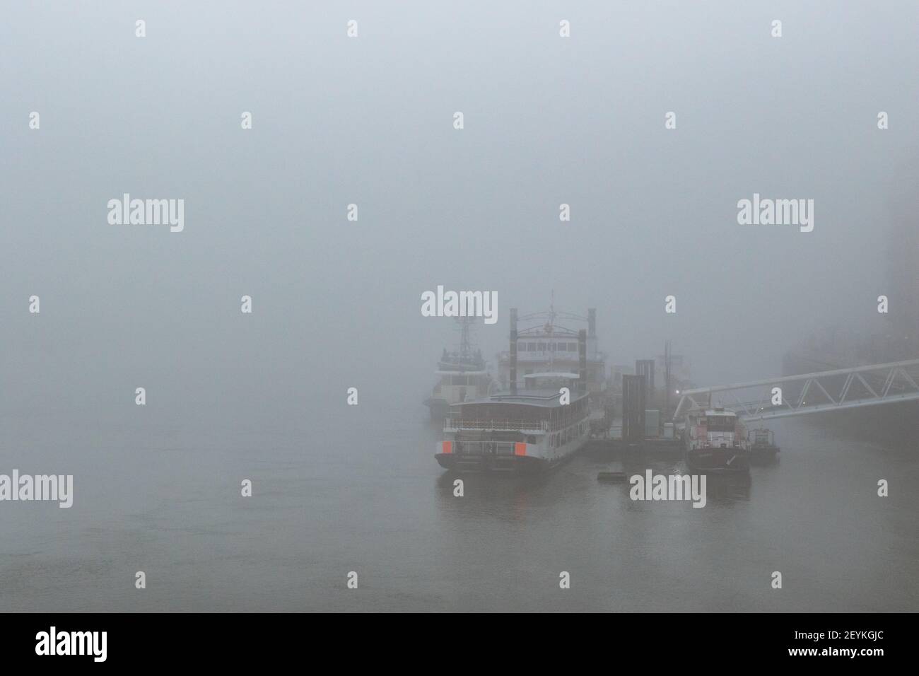 An impressionistic view of boats shrouded in mist, docked by Butlers Wharf in the Pool of London on the River Thames. With copy space - Stock Image