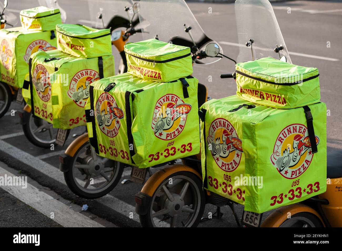 Florence, Italy - 2021, February 24: Scooters with pizza delivery bags, parked in a row. Stock Photo