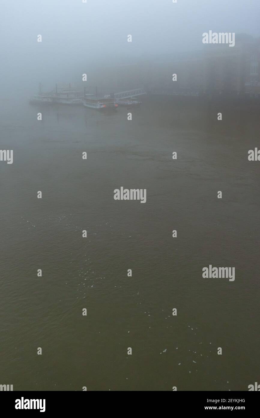 An impressionistic view of boats shrouded in mist, docked by Butlers Wharf in the Pool of London on the River Thames. With copy space - Stock Image
