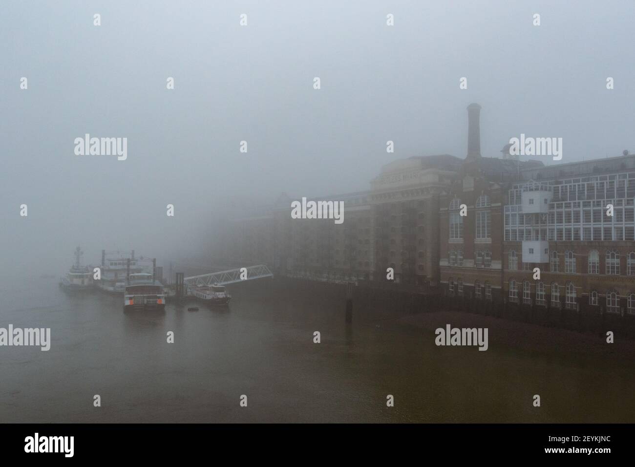 An impressionistic view of boats shrouded in mist, docked by Butlers Wharf in the Pool of London on the River Thames. With copy space - Stock Image