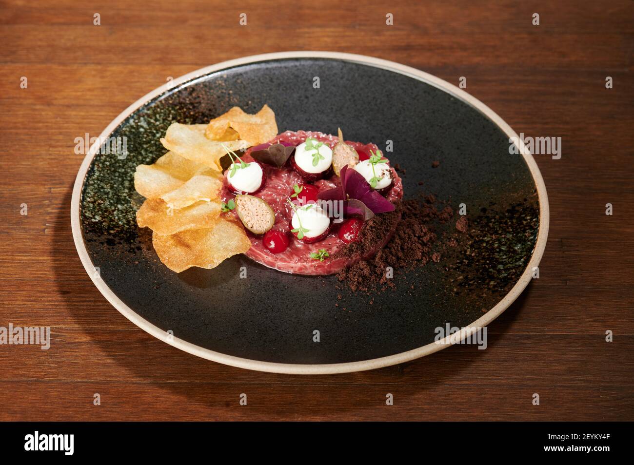 Meat tartare on black grunge plate perspective view Stock Photo