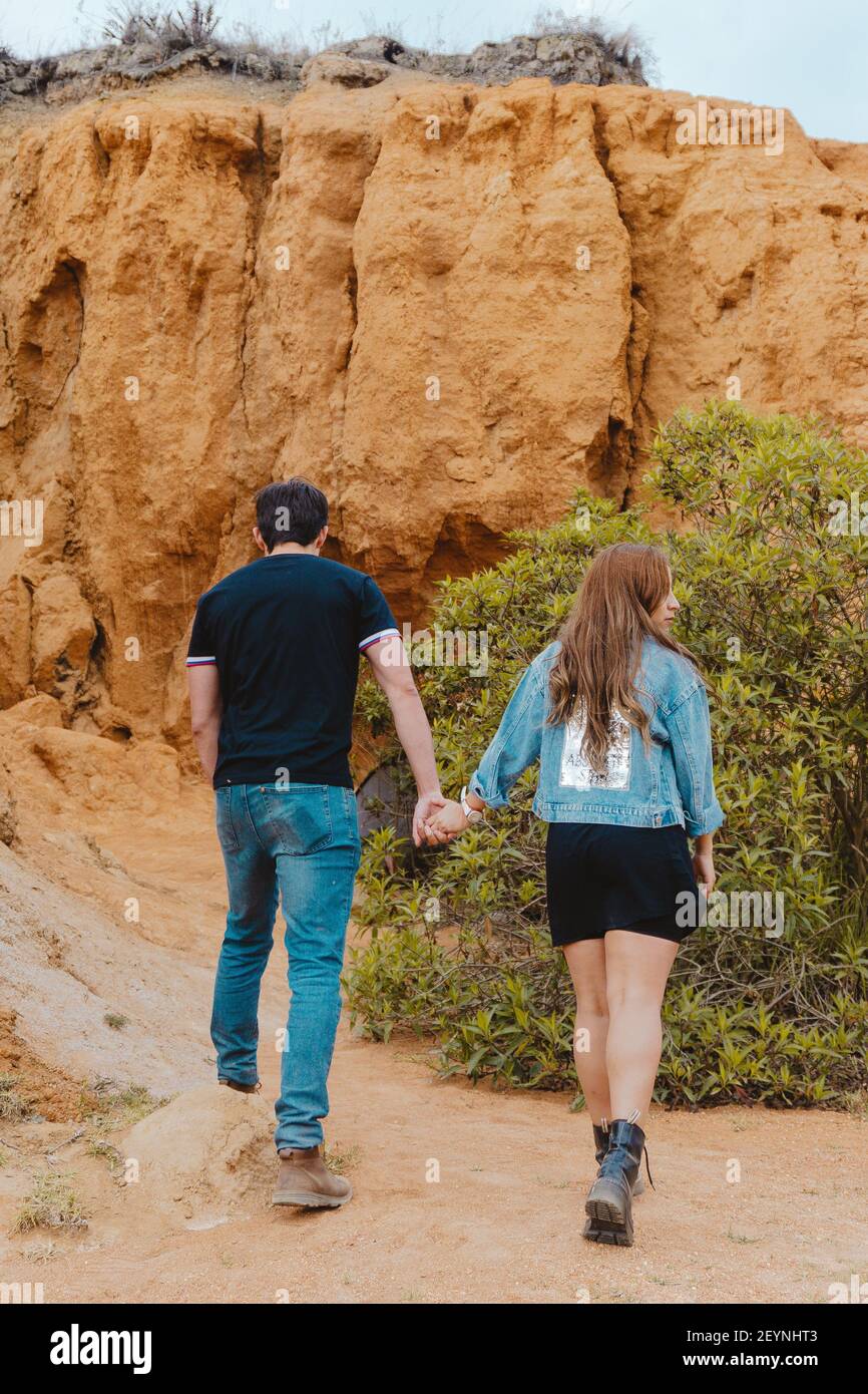 A vertical back view of a couple holding hands at the Sabrinsky desert in Colombia Stock Photo