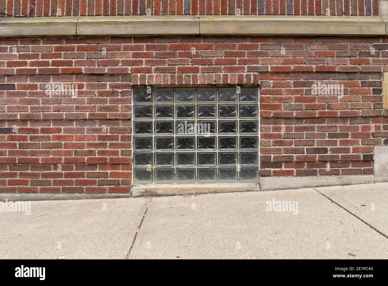 Straight on view of a glass block basement window in an old red brick ...