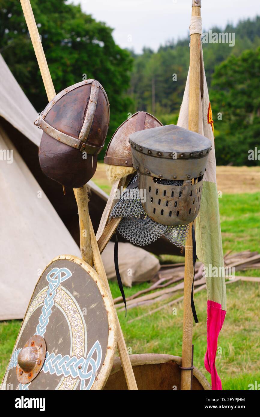 Early medieval 12th century great helm and medieval spangenhelm or skull cap with metal reinforcements in a re-enactment camp Stock Photo