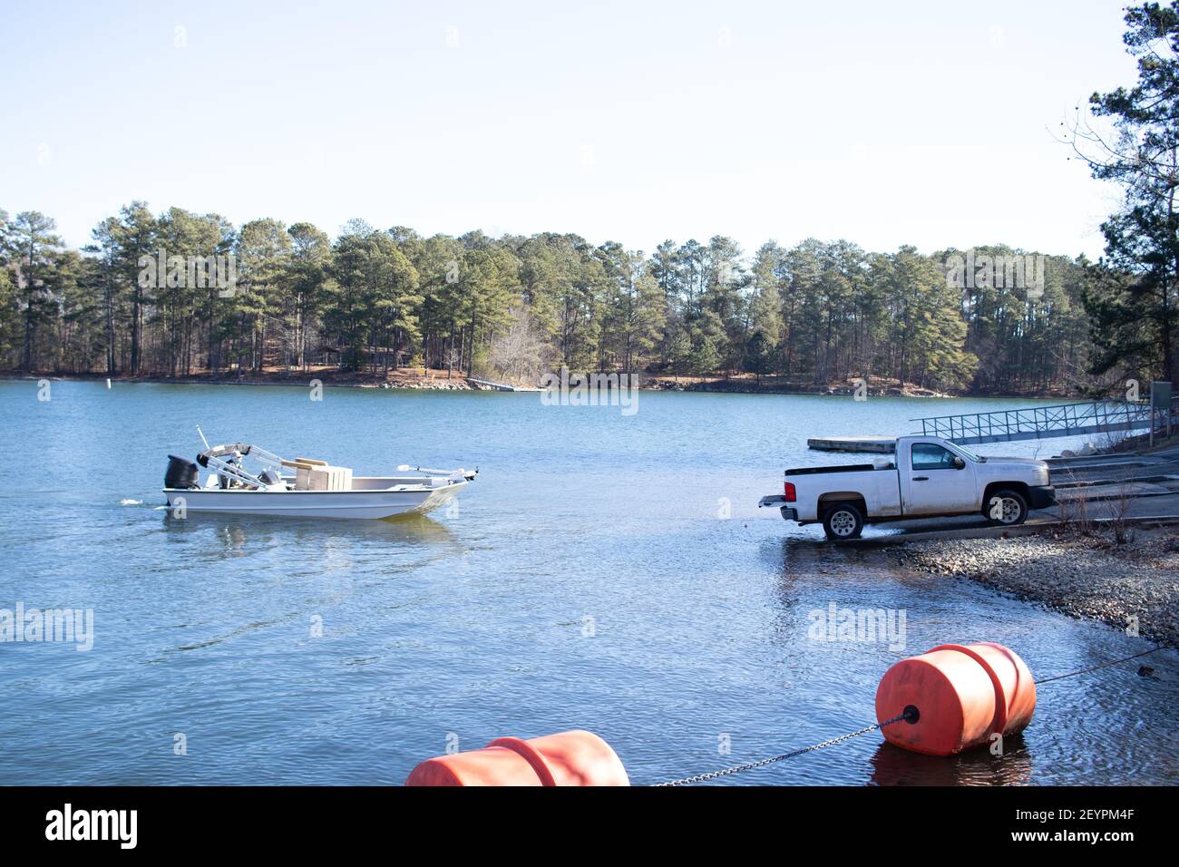 Pickup truck pulling boat and trailer out of the water at the shore of