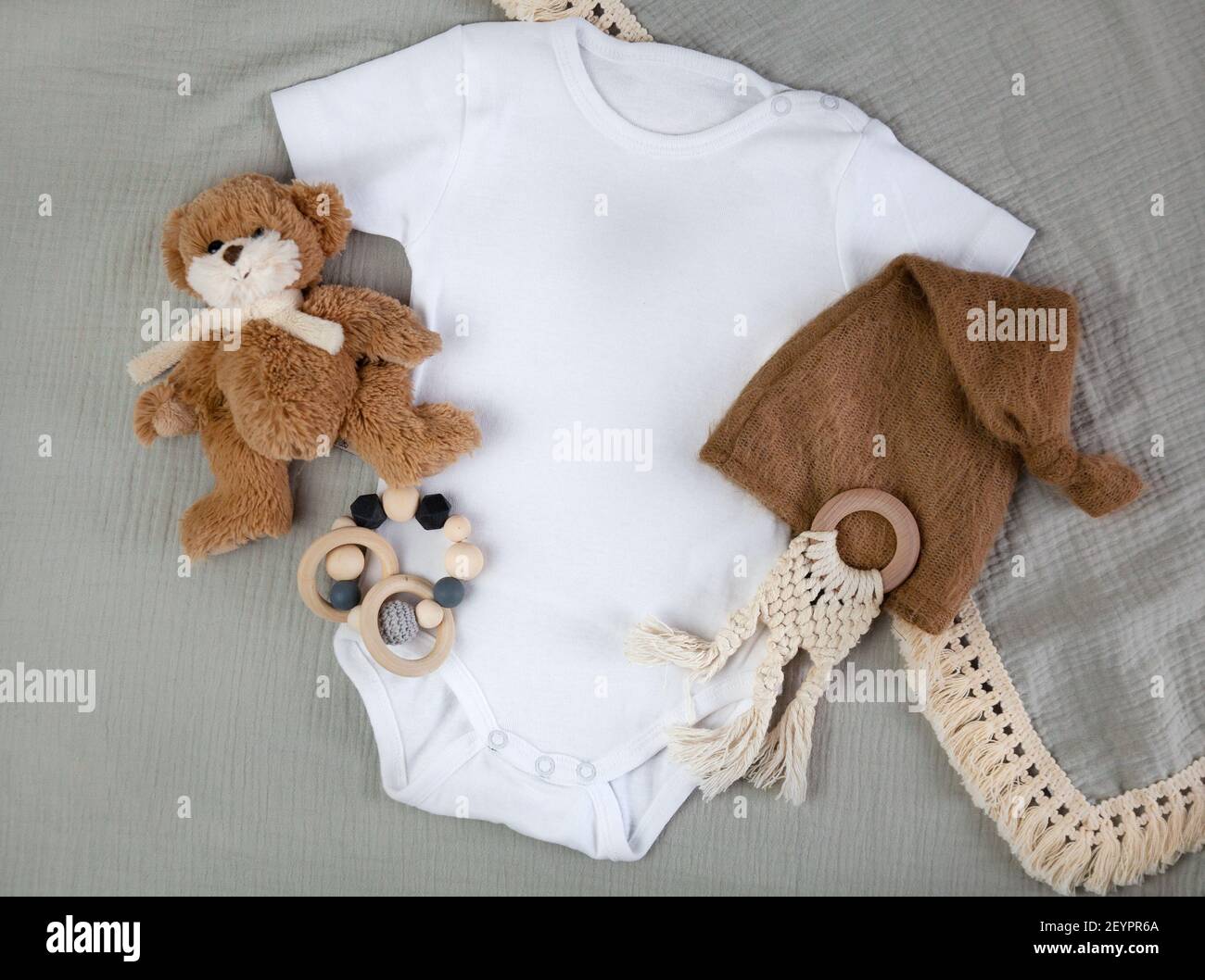 Title: White baby bodysuit. Organic cotton background, wooden toys, teddy bear. Styled baby clothing mock-up. Free space. Eco lifestyle. Stock Photo