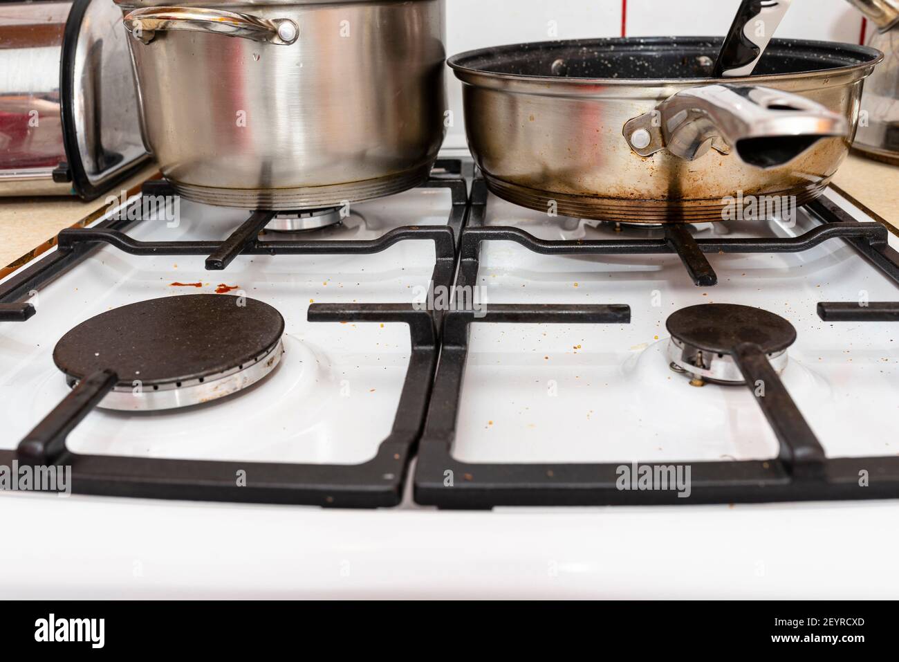 A stainless steel pot and frying pan standing on a switched off gas stove in the kitchen. Stock Photo