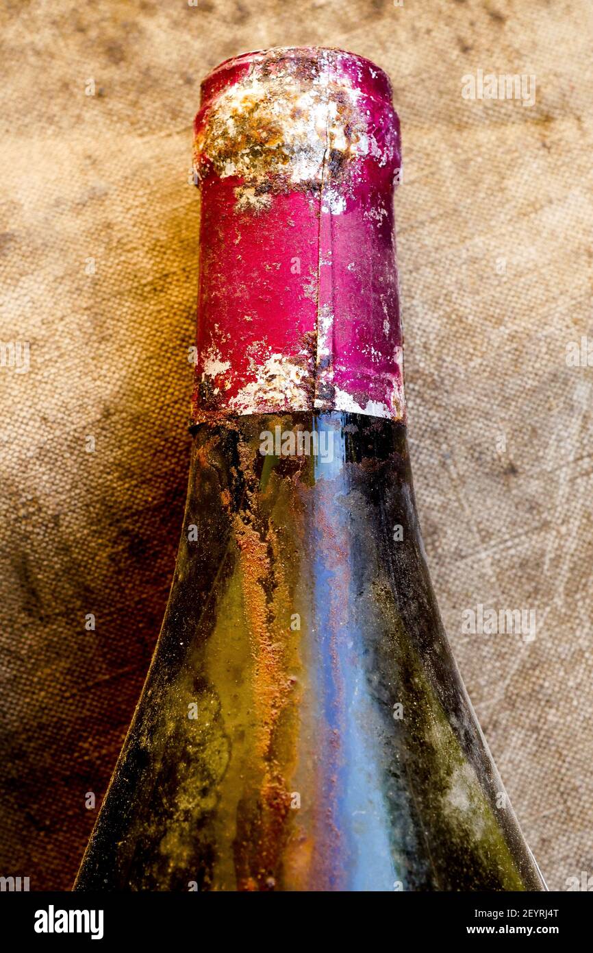 Bottleneck of an old red wine bottle with drops of wine laying of a