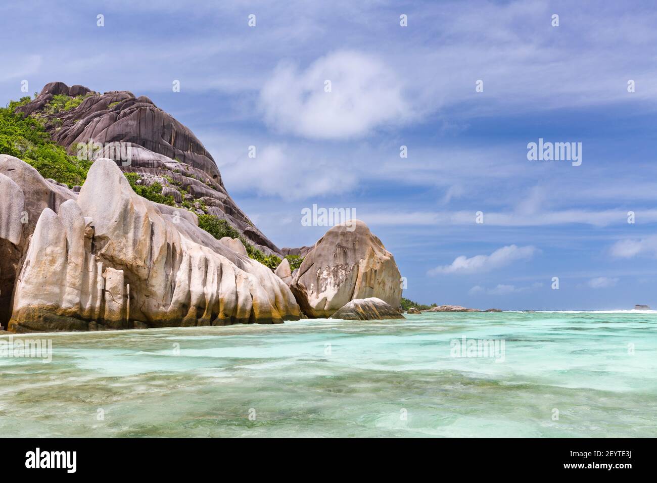 Turquoise water and coral reefs in front of the La Digue granite coastline, Seychelles Stock Photo