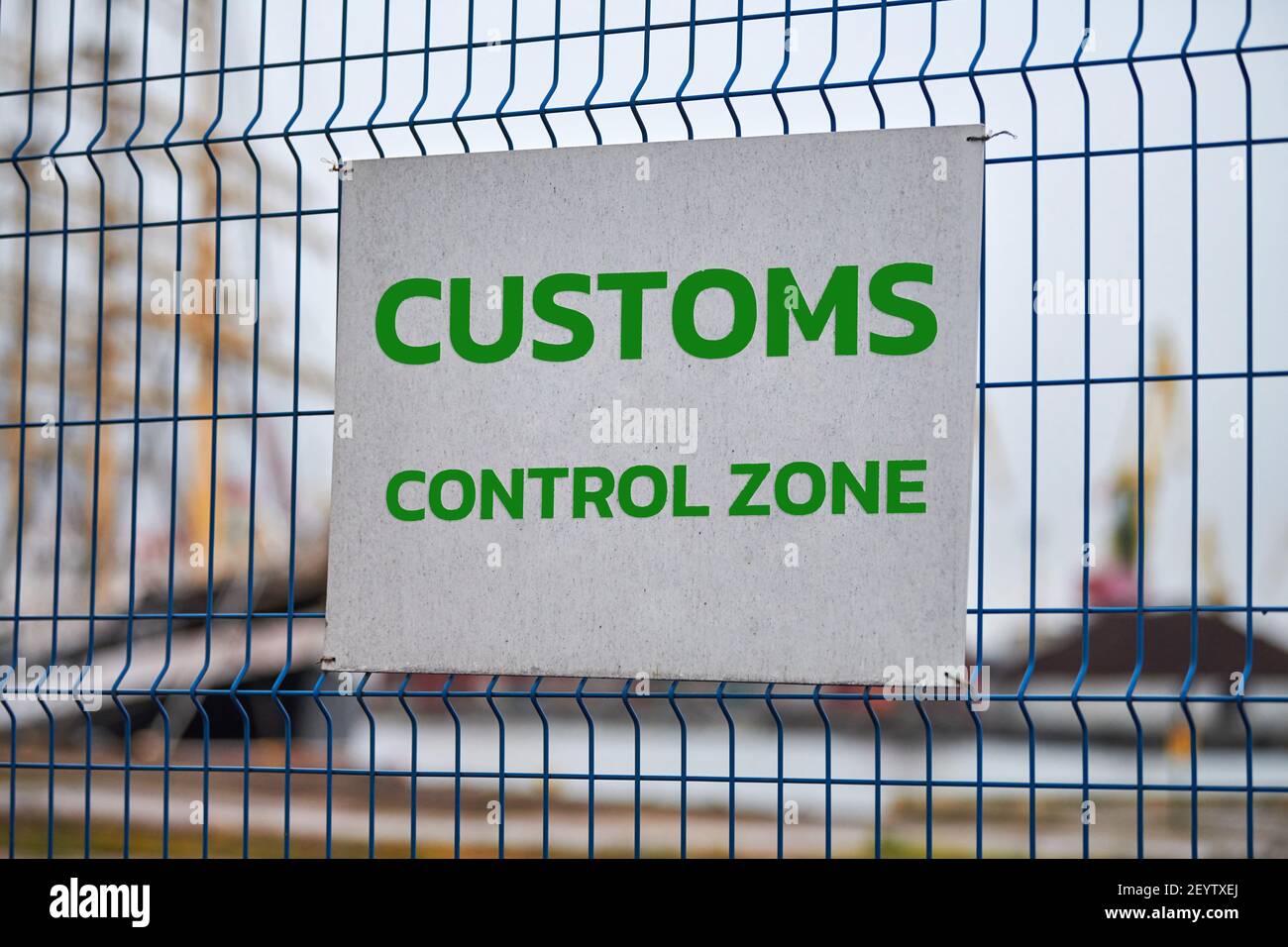 Customs control zone sign with green letters on metal fence, warning