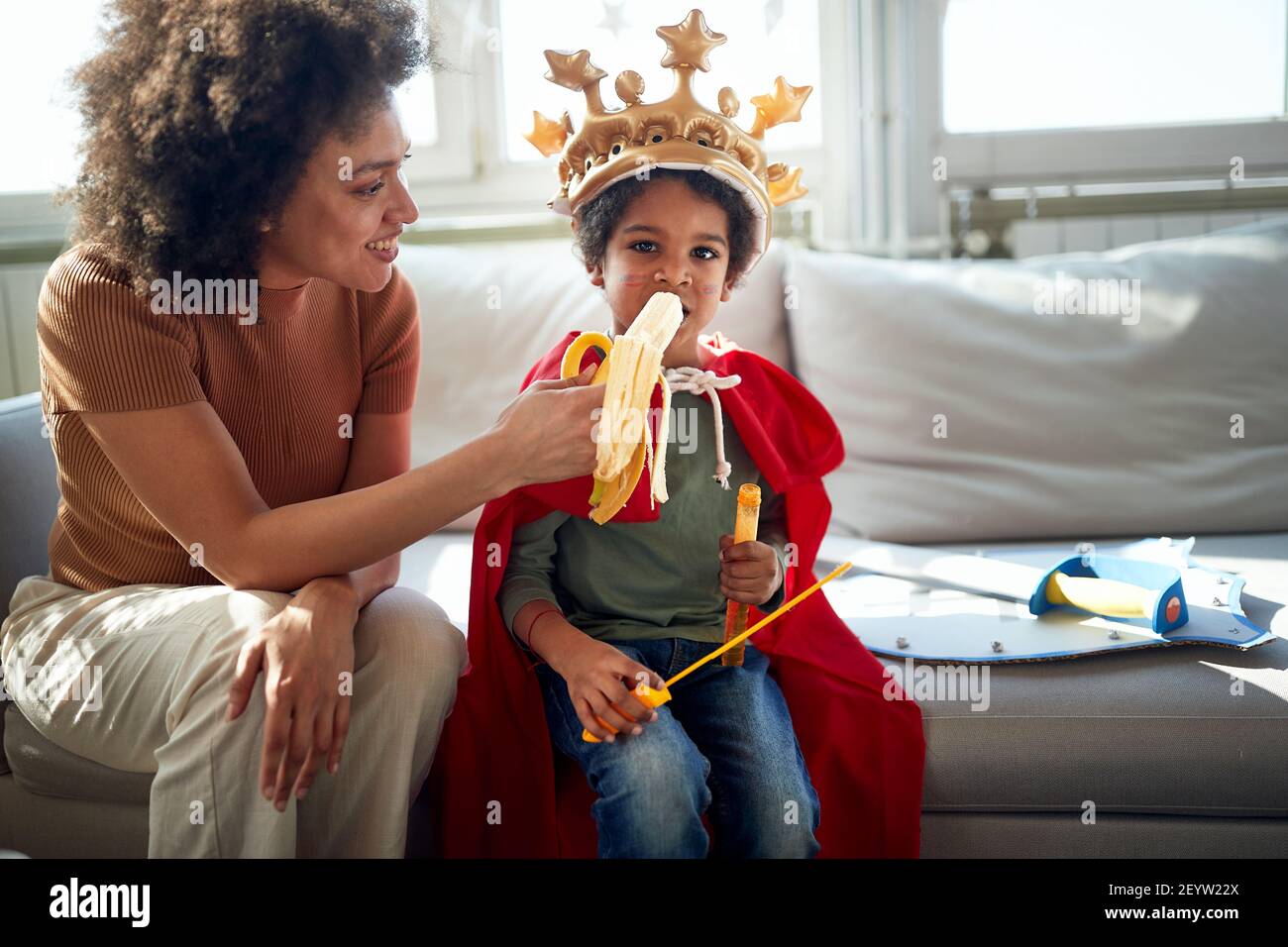 A little boy enjoying a banana while playing with his Mom in a relaxed atmosphere at home. Family, together, love, playtime Stock Photo