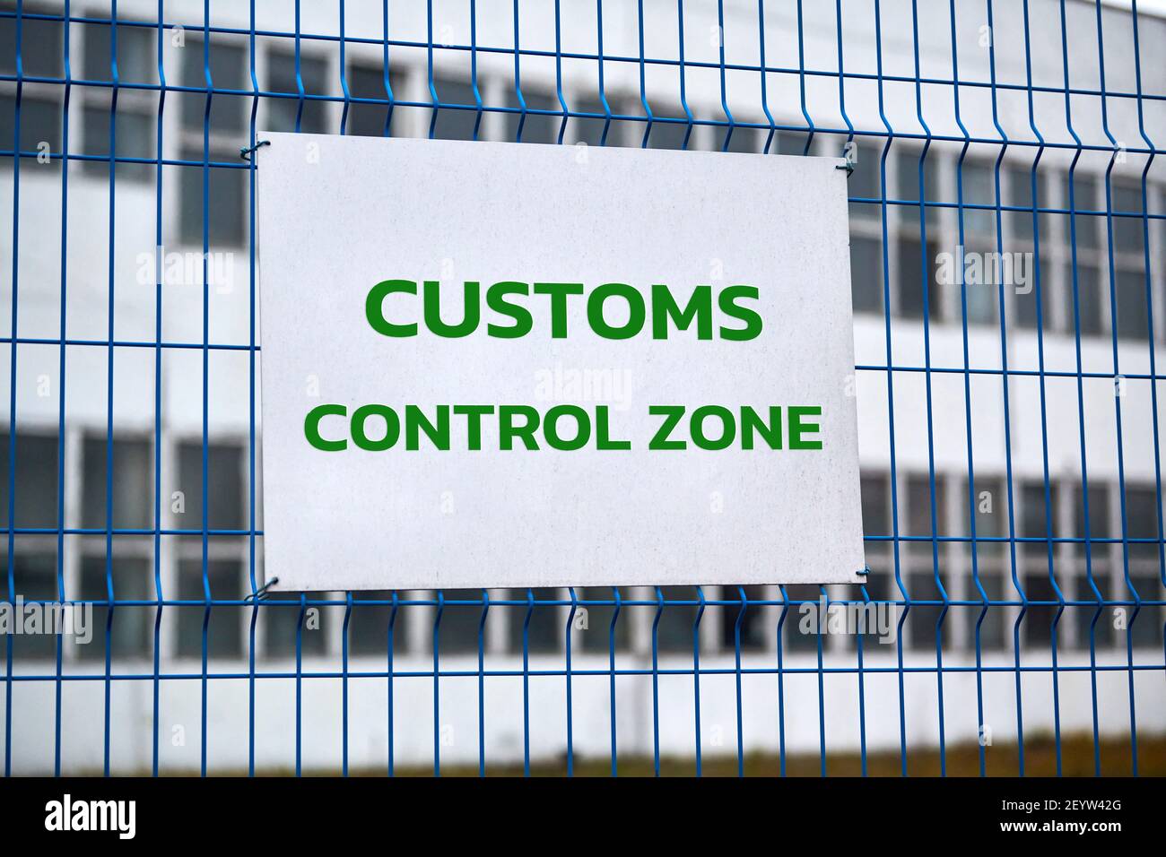 Customs control zone sign with green letters on metal fence, warning