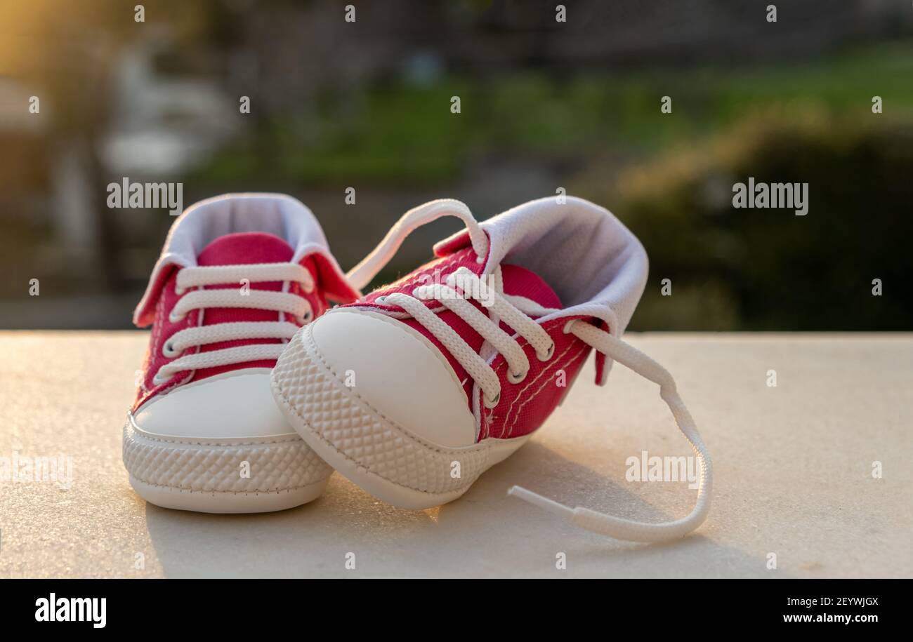 Booties baby sport shoes pink red color on white floor blur nature at sunset background. Kid small size sneakers outdoor active child Stock Photo Alamy