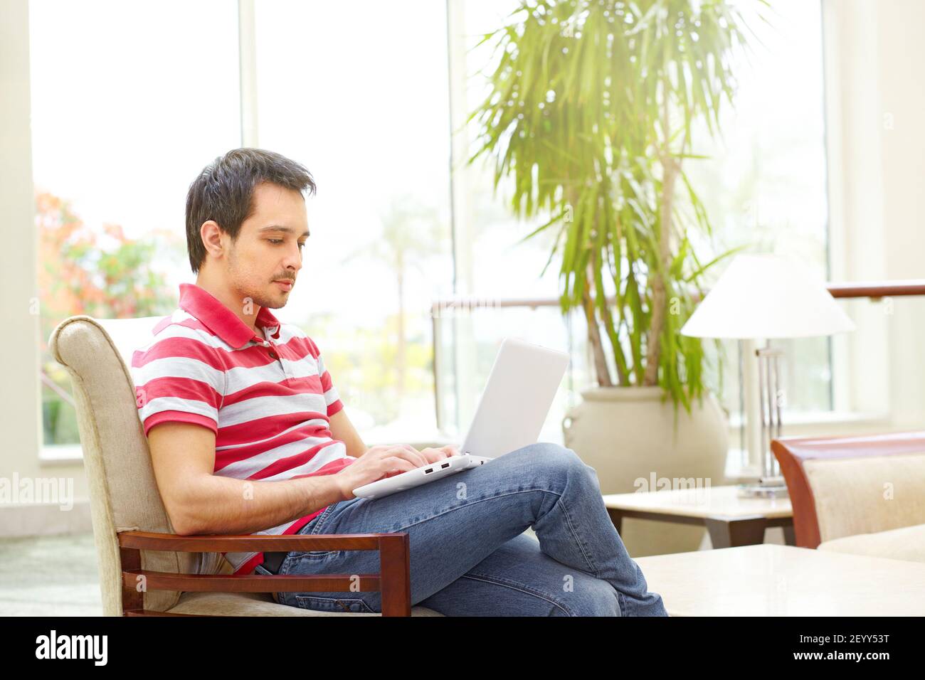 Handsome young man sits at bright hotel Stock Photo