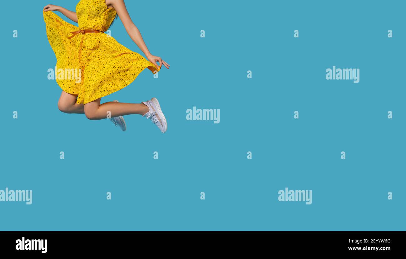 Girl with yellow dress jumping in the air isolated on blue background ...