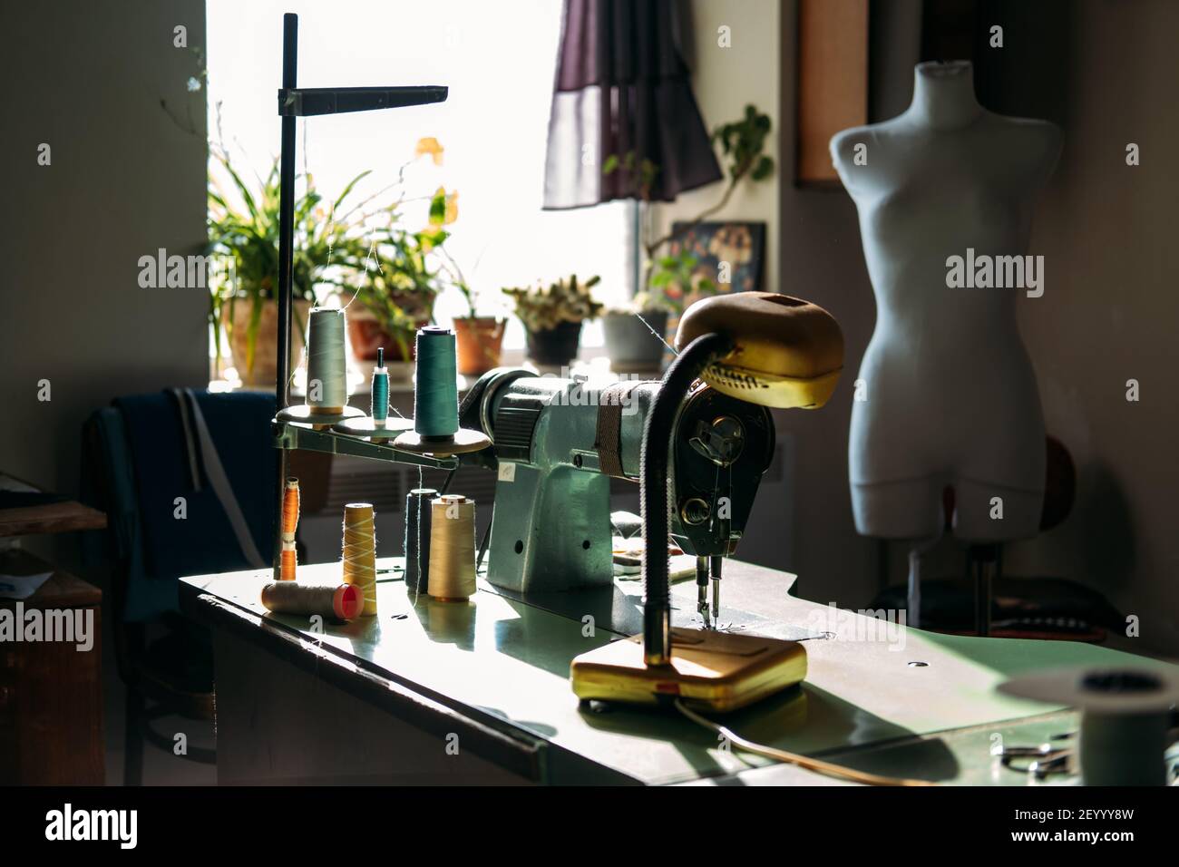 Sewing machine on table in factory in sun light. Small business, fashion designe, Tailor working, candid dressmaker workplace, Clothing or garment Stock Photo